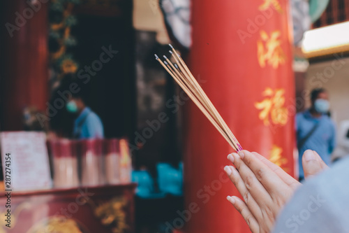 An asian woman keep a lotus, candles and incense sticks in hands for praying respect to the buddha statue