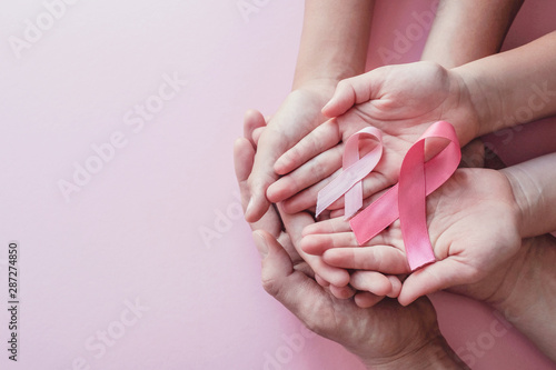 hands holding pink ribbons on pink background, Breast cancer awareness and October Pink day, World cancer day