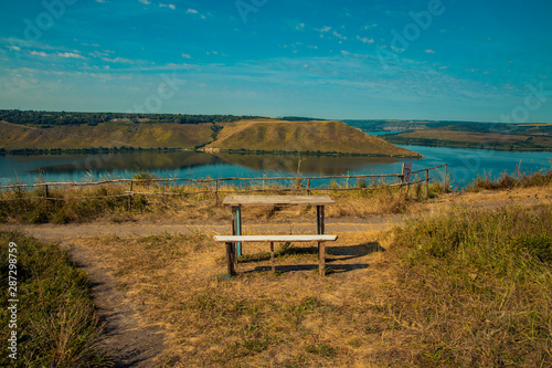 travel photography destination wooden bench and table with view on beautiful nature reserve scenic landscape territory with river and hill land background 