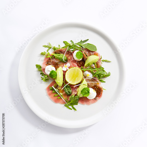 Tuna carpaccio with avocado and lime top view