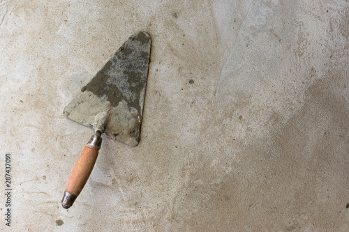 Construction tool for repairing trowels lies on gray-brown cement and concrete