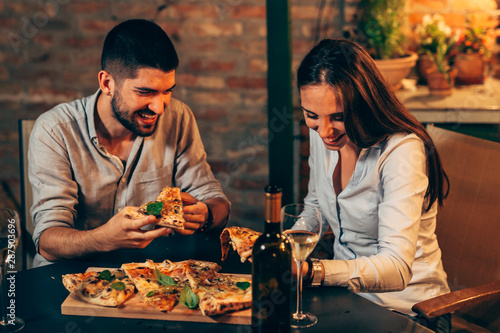 friends having hun at home eating pizza. outdoor at night