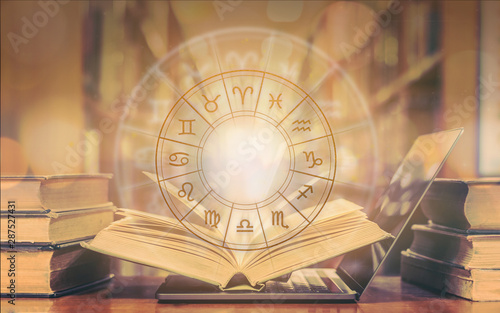 Online horoscope astrology and constellation study with zodiac sign for foretell and fortune telling education course concept with horoscopic wheel over old book and computer laptop in school library