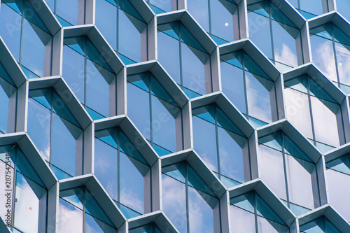 Office buildings. Structure of hexagon windows in futuristic technology network connection concept. Blue glass modern architecture facade design with reflection of sky in urban city, Downtown.