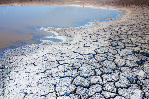 Heat, drought, disaster, saline soil, dry riverbed, blue sky reflected in the remnants of water. Bright, beautiful natural landscape. Close-up, background, Wallpaper, design. Selective focus.