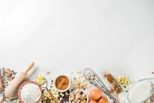 Ingredients for autumn winter festive baking - flour, brown sugar, eggs, chocolate drops, butter, cinnamon on stone or concrete background.Top view copy space.