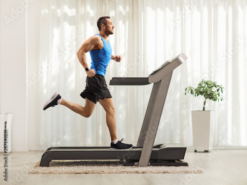 Young man running on a treadmill at home