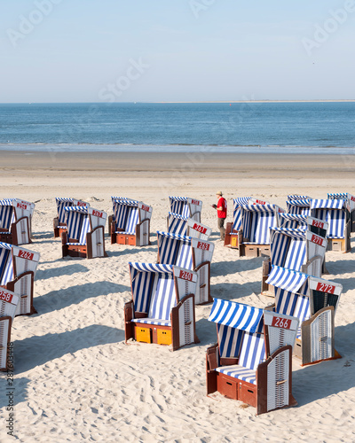 man in red shirt checks beach korbs on the island of norderney in germany on sunny day