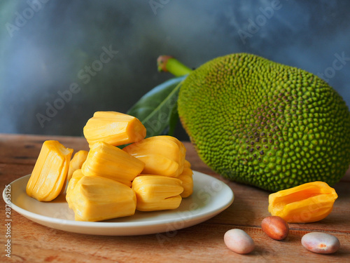 Ripe jackfruit flesh on white plate on wooden table for tropical fruit or meat substitute concept.