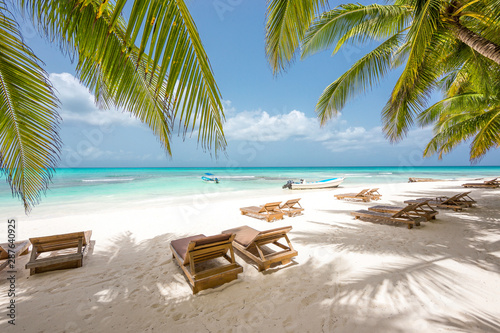 Chaise-longues on a beautiful white sand beach with coconut trees. Turquoise water of the Caribbean on the Saona island