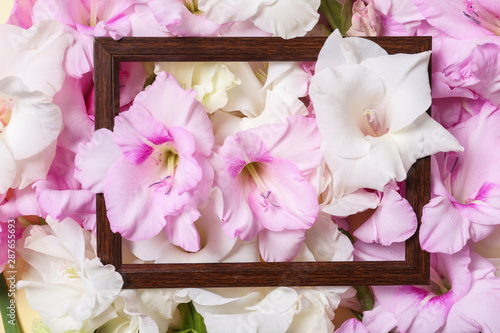 Top view of wooden frame and beautiful gladiolus flowers as background, closeup