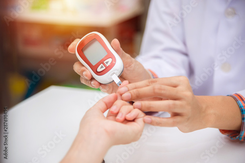 Hands of Pharmacist checking patient blood sugar by glucometer in drugstore