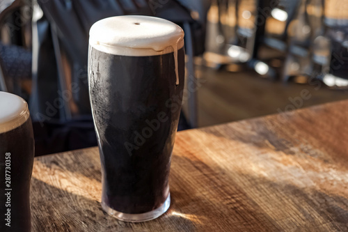 Glass of stout beer cloe-up standing on the wooden table