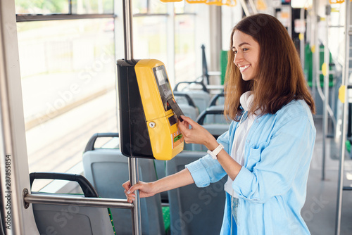 Young woman pays by bank card for the public transport in the tram or subway.