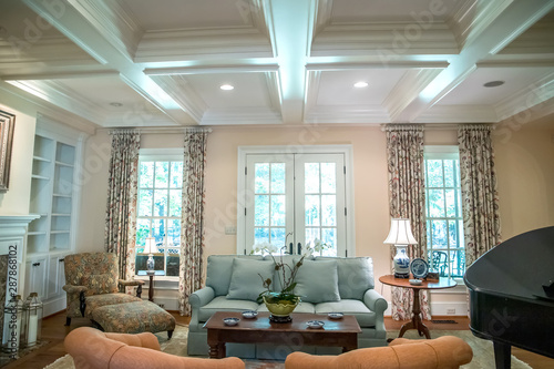large formal living room in a spacious home. Coffered ceiling and a lot of natural light from the large windows.