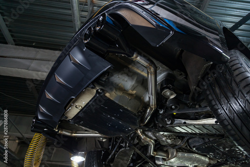 Bottom view of the car on a bifurcated exhaust system, rear bumper with a sports diffuser and nozzles in black. Tuning and atom service industry.