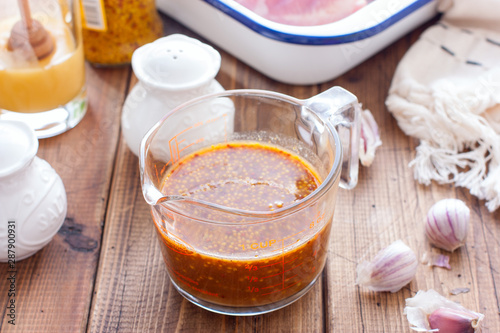 Honey mustard marinade in a transparent glass on a wooden table, selective focus