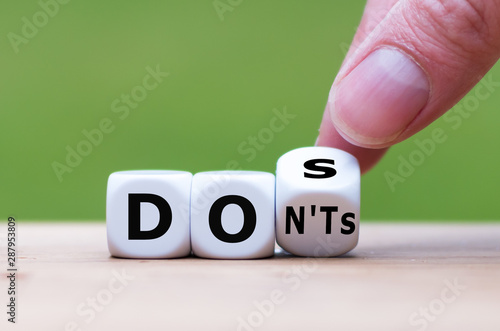 Hand flips a dice and changes the expression "don'ts" to "does"