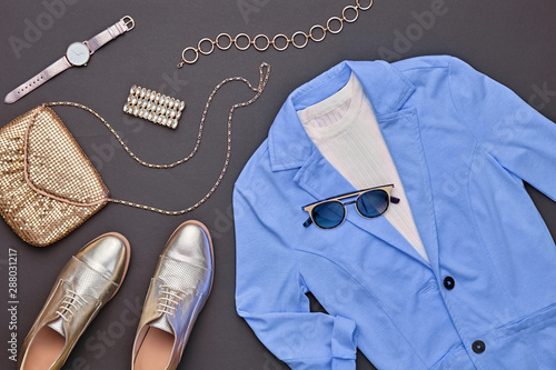 Autumn Arrives. Fall fashion Clothes Accessories Outfit. Creative Flat lay. Trendy blue jacket, Stylish gold loafers shoes, glamour handbag, fashionable party look. Autumnal color, shopping concept
