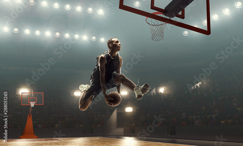 African american basketball player in action on a floodlit court. Slam dunk 