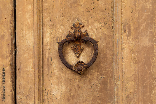 Italy, Apulia, Province of Lecce, Galatina. Rusty knocker on an old weathered wooden door.