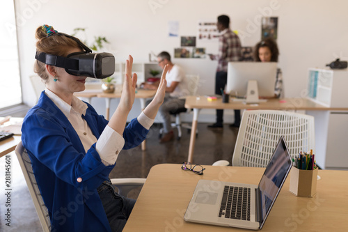 Businesswoman using virtual reality headset at desk