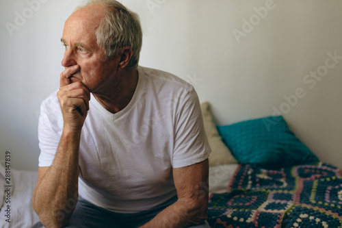 Senior male patient sitting on bed at retirement home