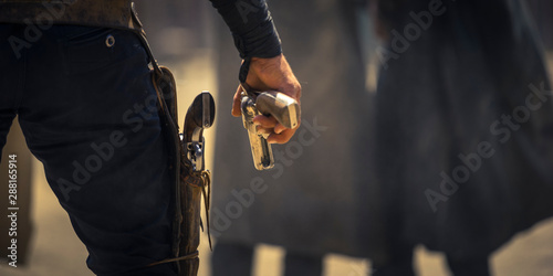 Man holding his six-shooter ready for a gunfight, Western movie set
