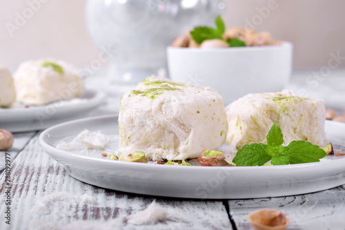 Cotton candy with pistachio on ceramic plate on white wooden table