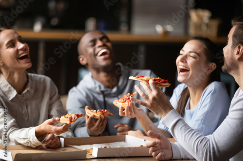Diverse friends eating pizza and having fun together in cafe