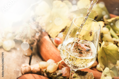 White wine being poured into a glass, vintage wood background, selective focus