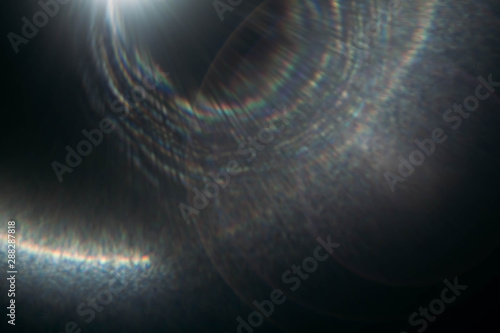 Blur rainbow lens flare on dark abstract background. Round spotlight rays and beams effect.