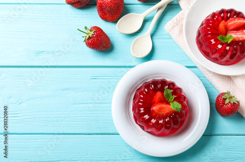 Delicious red jelly with strawberries and mint on light blue wooden table, flat lay. Space for text