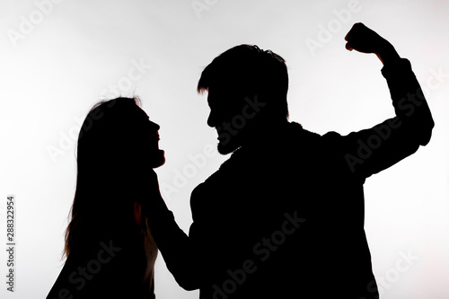 Domestic violence and abuse concept - Silhouette of man beating defenseless woman