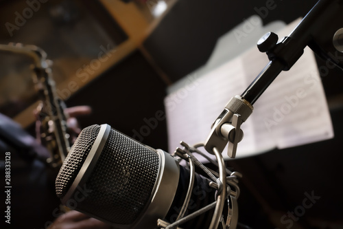 Microfono e musicista con sassofono e spartito in studio di registrazione