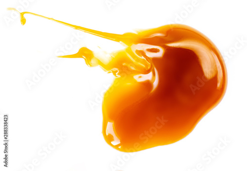 Melted caramel sauce isolated on a white background. Spilled maple syrup. Close up.