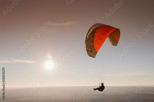 Paraglide with a paraglider in a cocoon against the background of fields of the sky and clouds. Paragliding Sports