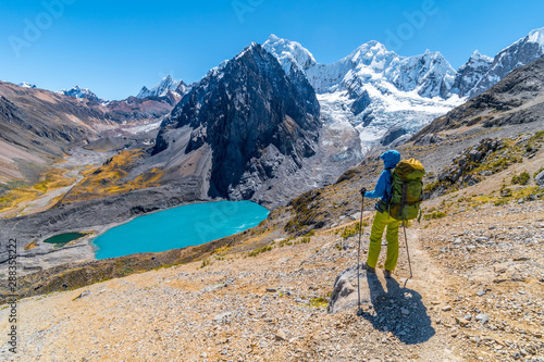 Girl hiking by stunning lake Juraucocha, San Antonio pass with view to Siula Grande peak, Huayhuash range, Huaraz, Ancash, Peru