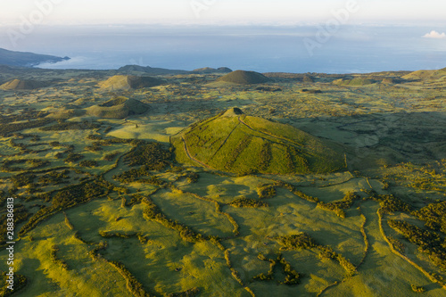 Aerial image of typical green volcanic caldera crater landscape with volcano cones of Planalto da Achada central plateau of Ilha do Pico Island, Azores