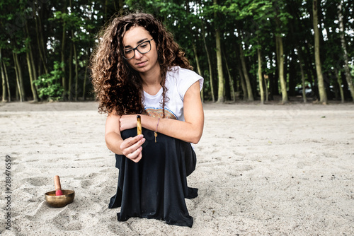 Kobieta trzyma palące się kadzidło, Palo Santo. Ceremonia, rytuał na plaży, natura.