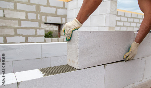 A worker lays foam concrete bricks in a house under construction
