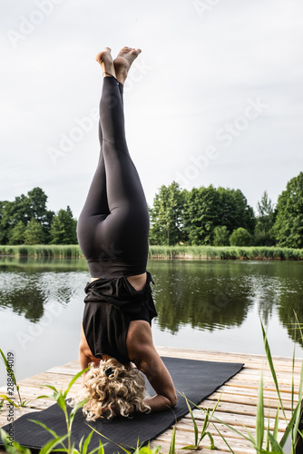 Kobieta uprawiająca jogę i medytację na świeżym powietrzu. Asana nad jeziorem. Instruktor jogi. 