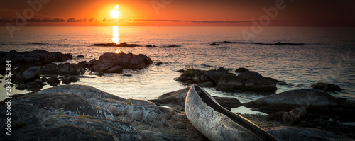 sunrise view at the Lake Malawi, waves rolling smoothly on the beach, wooden one tree boat in the foreground, Africa, Panorama