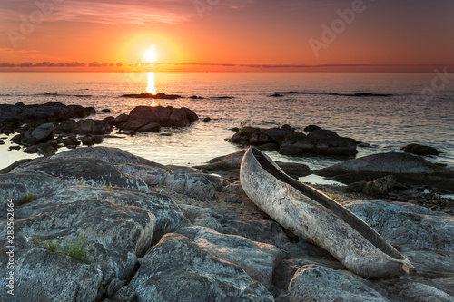 sunrise view at the Lake Malawi, waves rolling smoothly on the beach, wooden one tree boat in the foreground, Africa,