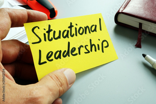 Man holds sign Situational Leadership on a yellow piece of paper.