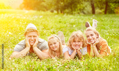 Familie und Kinder liegen im Garten im Gras