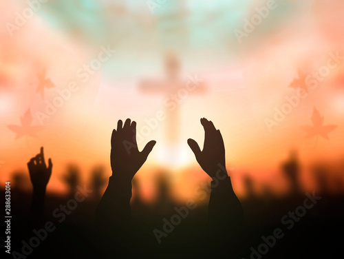 Worship concept: human rising hands over blurred cross background