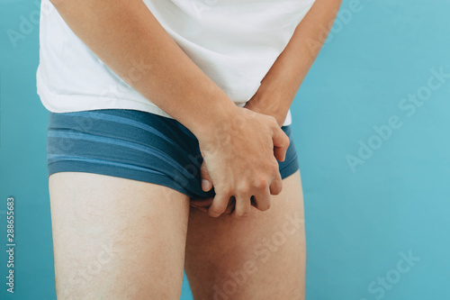 man wearing underpants holding genitals. urological diseases, pain during urination