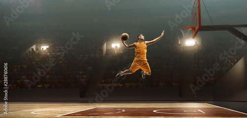 Professional basketball player on sports arena in action with the ball. Slam dunk