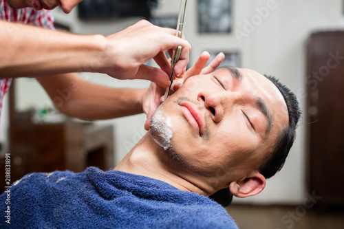 Hairdresser shaves man's beard